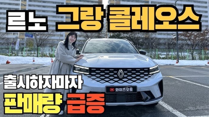 여성이 흰색 르노 그랑 콜레오스 차량 앞에서 포즈를 취하고 있으며, 상단에는 '르노 그랑 콜레오스'라는 큰 글씨와 하단에 '출시하자마자 판매량 급증'이라는 문구가 있음.