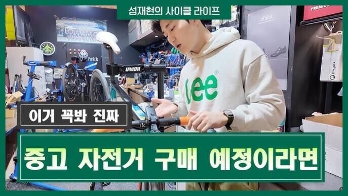 자전거 가게에서 후드티를 입은 남성이 자전거를 점검하고 있으며, 화면에는 '이거 꼭봐 진짜 중고 자전거 구매 예정이라면'이라는 문구가 크게 표시되어 있다.