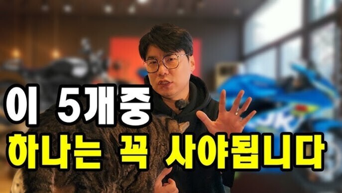 안경을 쓴 남성이 다섯 개의 손가락을 펴 보이며 고양이와 함께 서 있고, 배경에는 오토바이가 있으며 '이 5개중 하나는 꼭 사야됩니다'라는 문구가 크게 적혀 있다.
