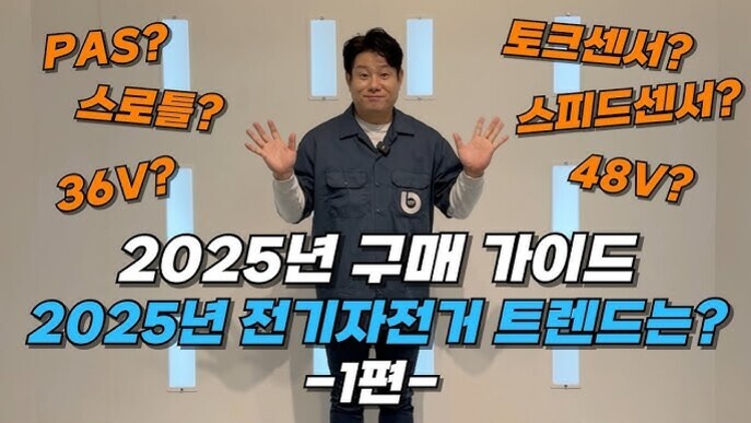한 남성이 벽 앞에 서서 양손을 들고 있다. 이미지에는 '2025년 구매 가이드 2025년 전기자전거 트렌드는? -1편-'이라는 글자가 크게 적혀 있고, 주변에 PAS?, 스로틀?, 36V?, 토크센서?, 스피드센서?, 48V?라는 텍스트가 각기 흩어져 있다.